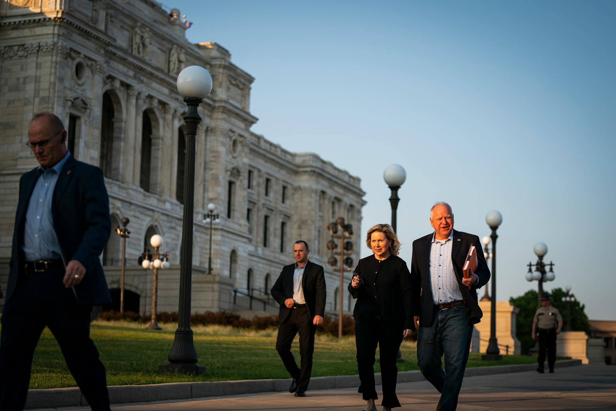 Gov. Tim Walz, right, with his wife, Gwen Walz, walk the signed education budget law over to the office of Secretary of State Steve Simon, from the Capitol, Wednesday, June 30, 2021, in St. Paul, Minn. (Leila Navidi/Star Tribune via AP)