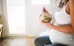 Beautiful pregnant woman eating healthy food and salads