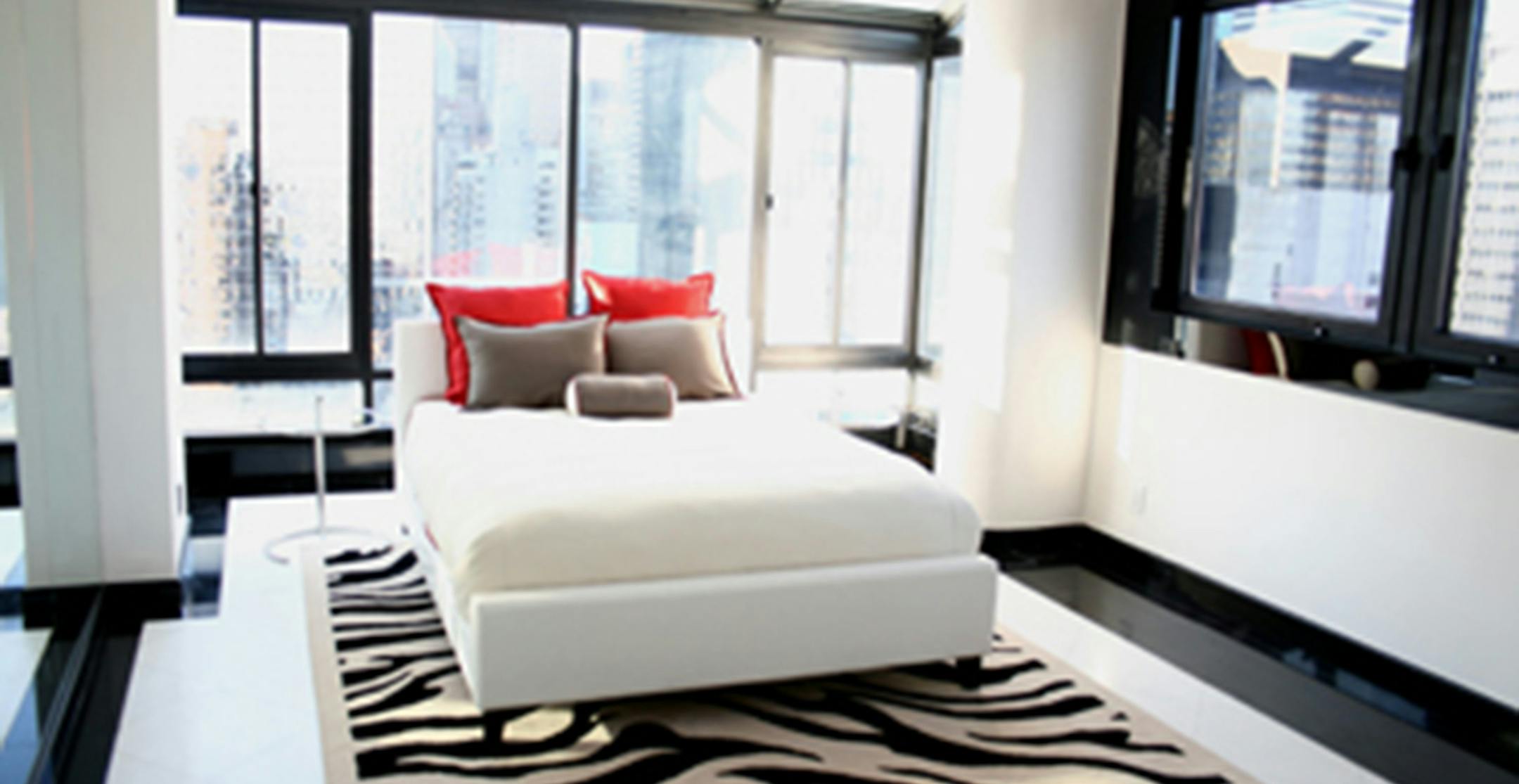 A pop of red through the use of toss pillows perks up this black and white-inspired bedroom. (Handout/TNS) ORG XMIT: 1179985