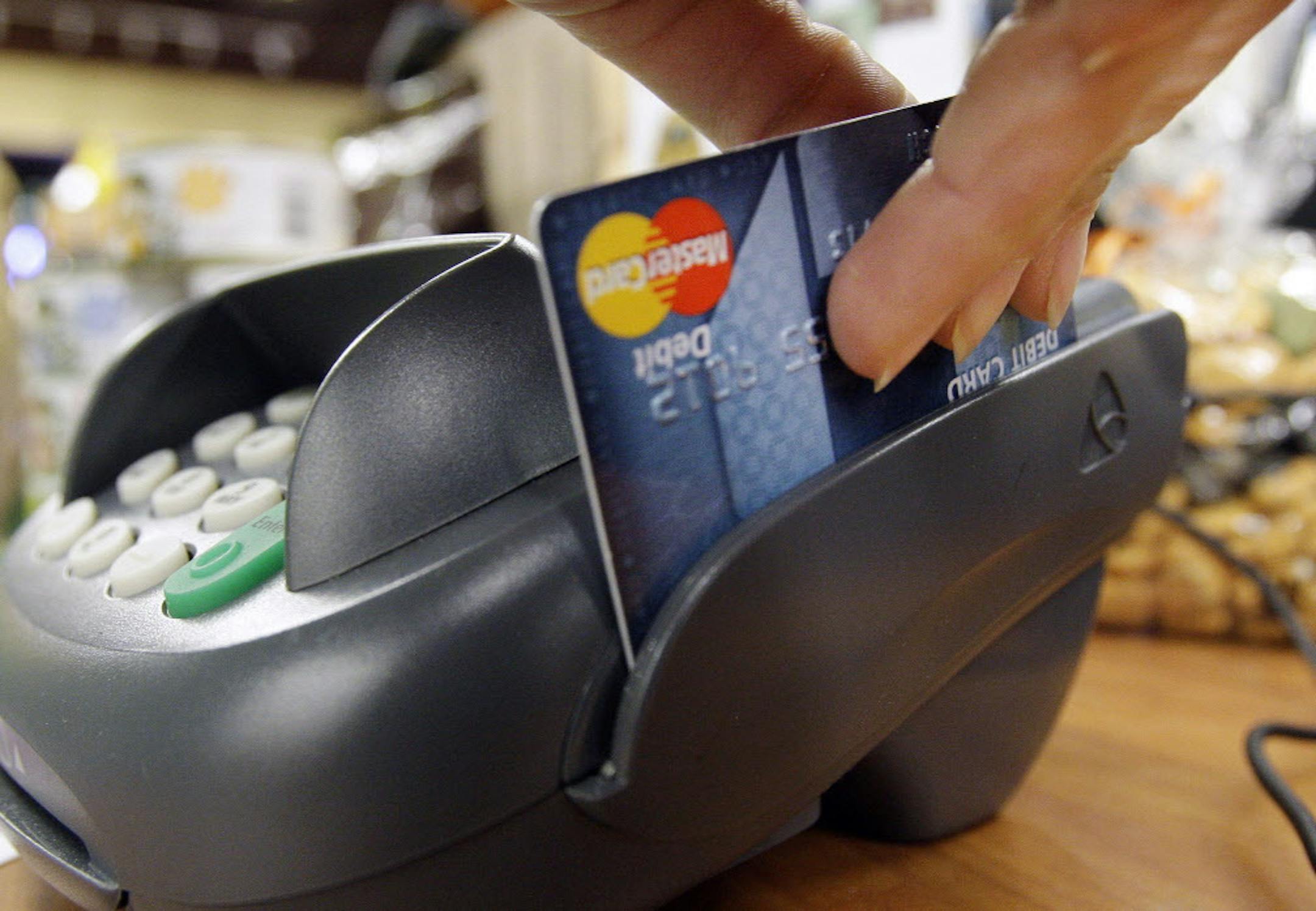 FILE - In this Nov. 2, 2009 file photo, a customer swipes a MasterCard debit card through a machine while checking-out at a shop in Seattle. Bankers and merchants, pillars of the business world and frequent allies, are engaged Thursday, March 10, 2011,in a bitter lobbying war over something Americans do 38 billion times a year _ swipe a debit card.(AP Photo/Elaine Thompson, file) ORG XMIT: MIN2013082117281592