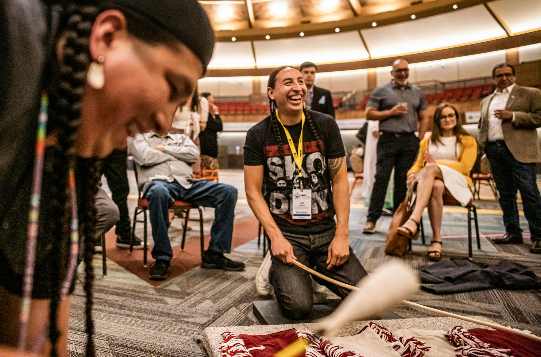Under the direction of Shakopee Mdewakanton Sioux Community employee Will Crawford playing a drum, Joel Moffett of the Nez Perce Tribe plays a game of moccasin in which the object is to find a coin hidden under one of the opponent's blanket in Shakopee, Minn., on Wednesday, June 7, 2023. Moffett is a Director of Environmental Projects at the nonprofit Native Americans in Philanthropy.