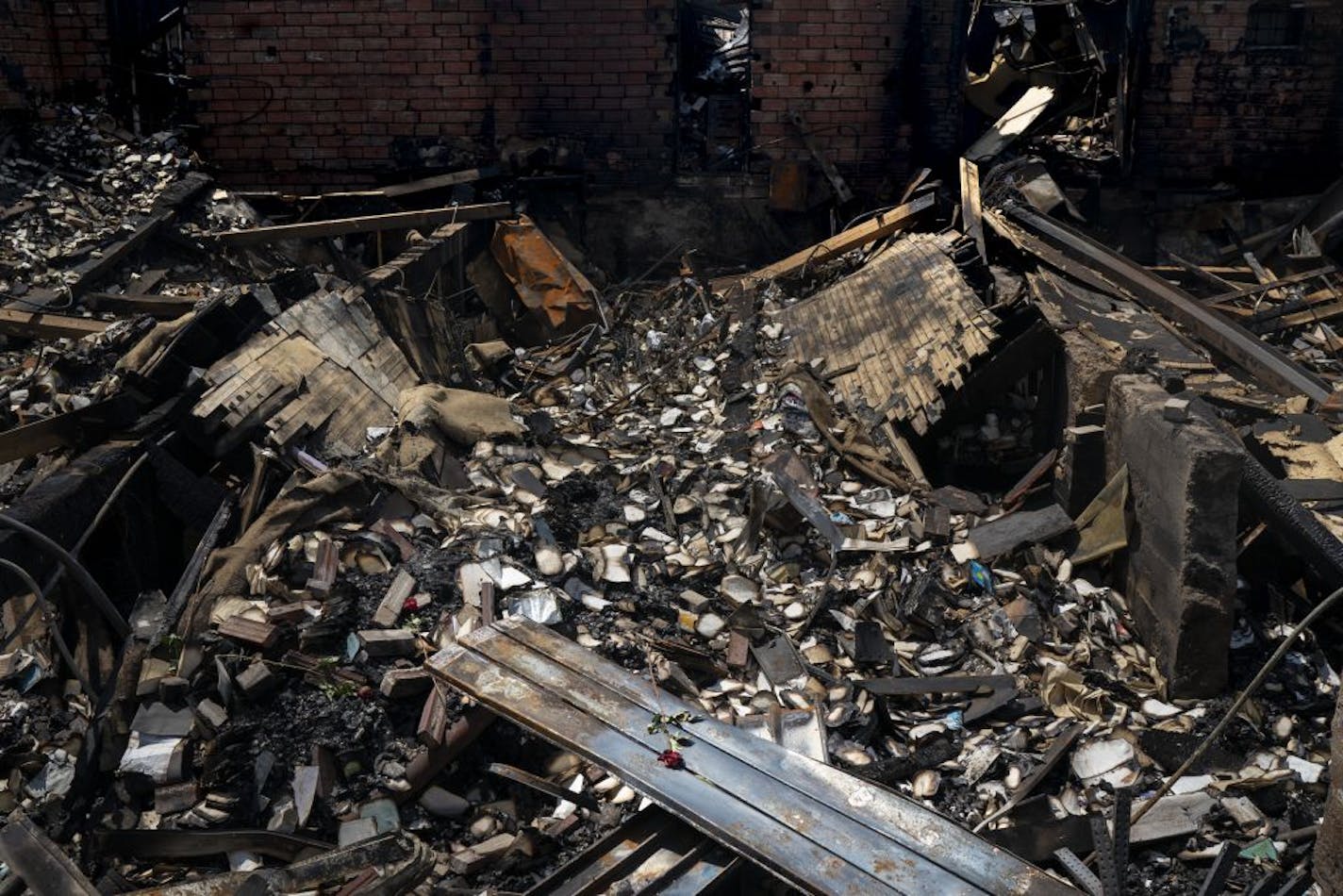 A single rose stands out on the burnt remains of twin bookstores Uncle Hugo's and Uncle Edgar's in Minneapolis on Tuesday. Someone had sprinkled roses throughout the rubble.