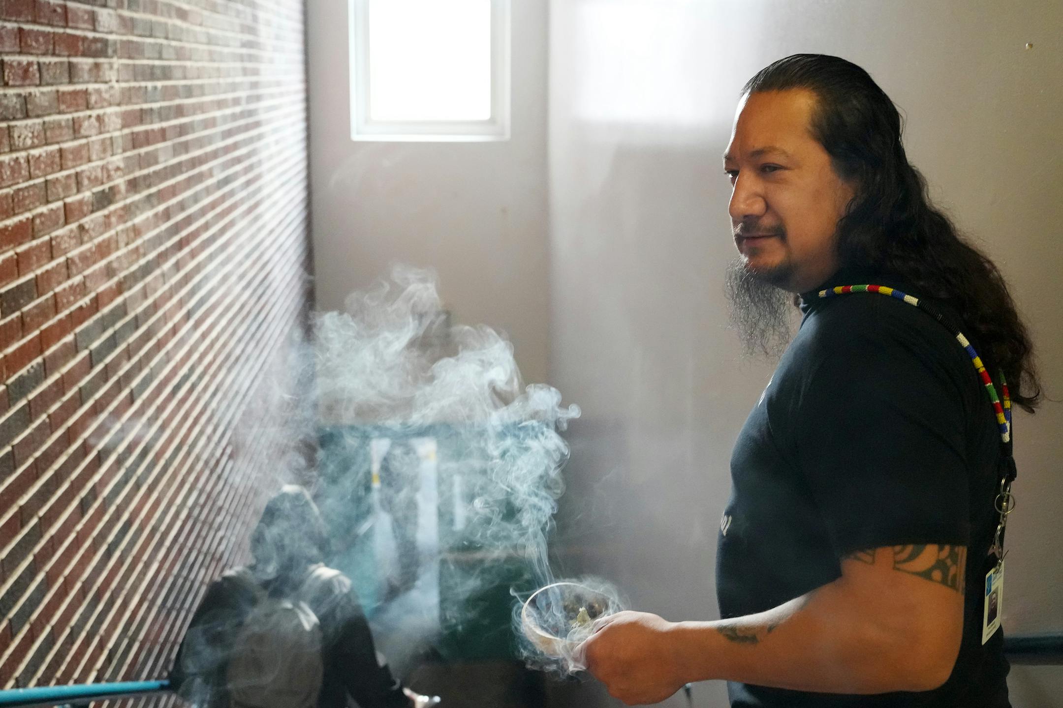Thomas Draskovic, the kindergarten through fourth grade Lakota language and culture specialist at the American Indian Magnet School, walks through the halls as he smudges the school on the first day of class.