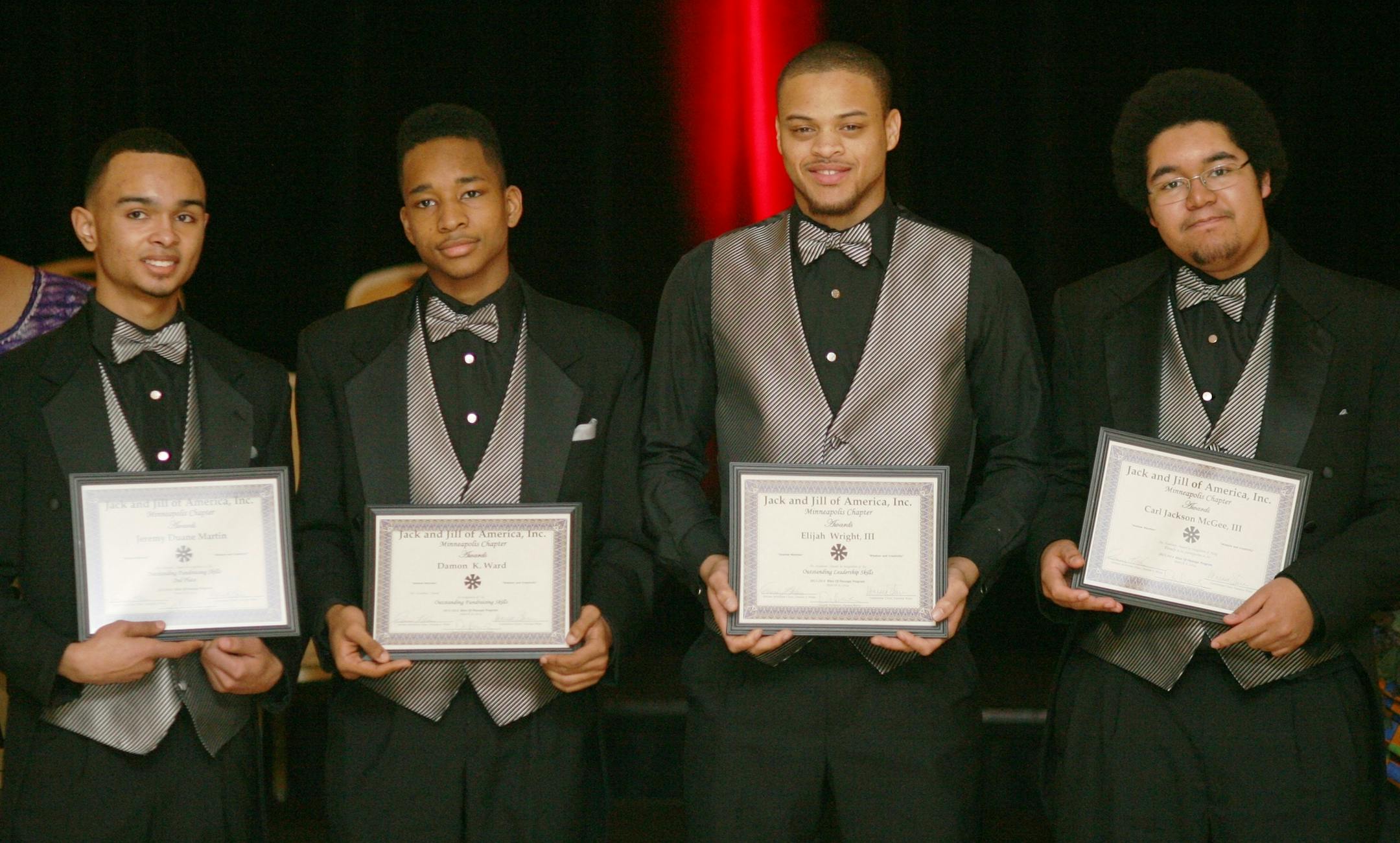 As Vanessa Ware looks on, initiates Jeremy Martin, Damon K. Ward, Elijah Wright III and Carl Jackson McGee III hold awards they received at the 16th annual Rites of Passage ceremony held March 8, 2014, at the Marriott in Minnetonka.