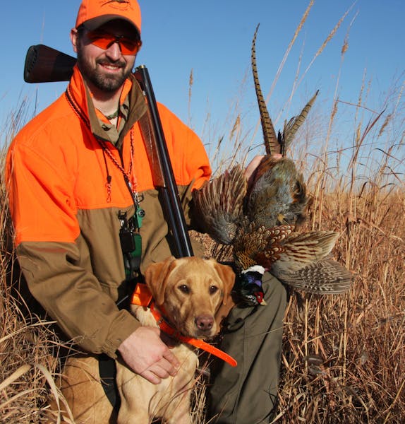 Andrew Vavra, 27, of Minneapolis and his Lab "Beau" with a rooster pheasant. Vavra and two other Pheasants Forever employees are doing a five-state-in