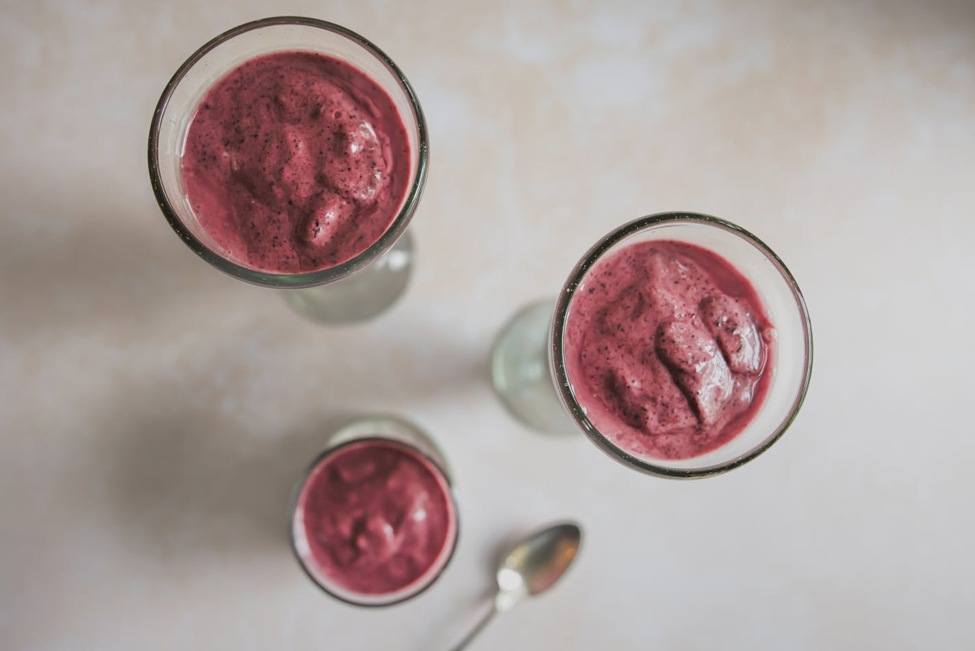 Three chilled glasses filled with blueberry-avocado smoothies.