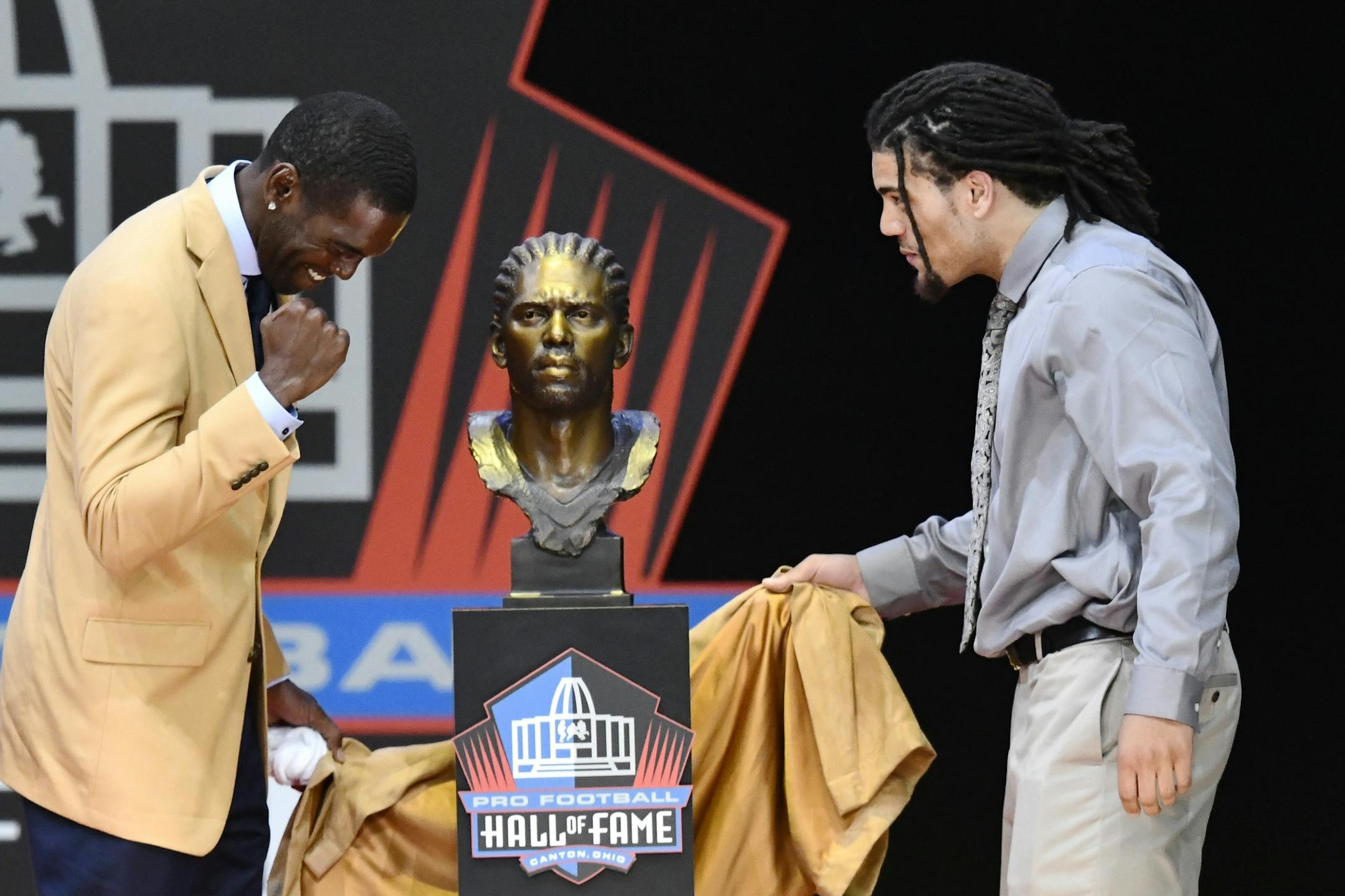Former NFL wide receiver Randy Moss, left, unveils his bust with his presenter, son Thaddeus Moss, during inductions at the Pro Football Hall of Fame on Saturday, Aug. 4, 2018, in Canton, Ohio.