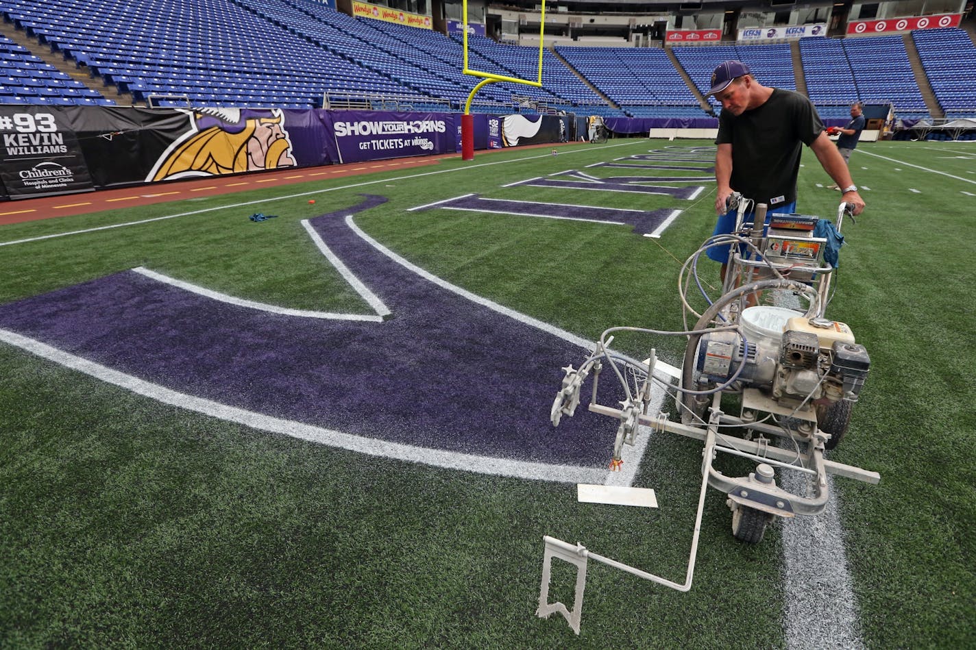 Wayne Enger of the Metrodome grounds crew outlined the Vikings endzone letters with a spray painter, during the first painting of the field Tuesday for the final season of the Vikings at the stadium.