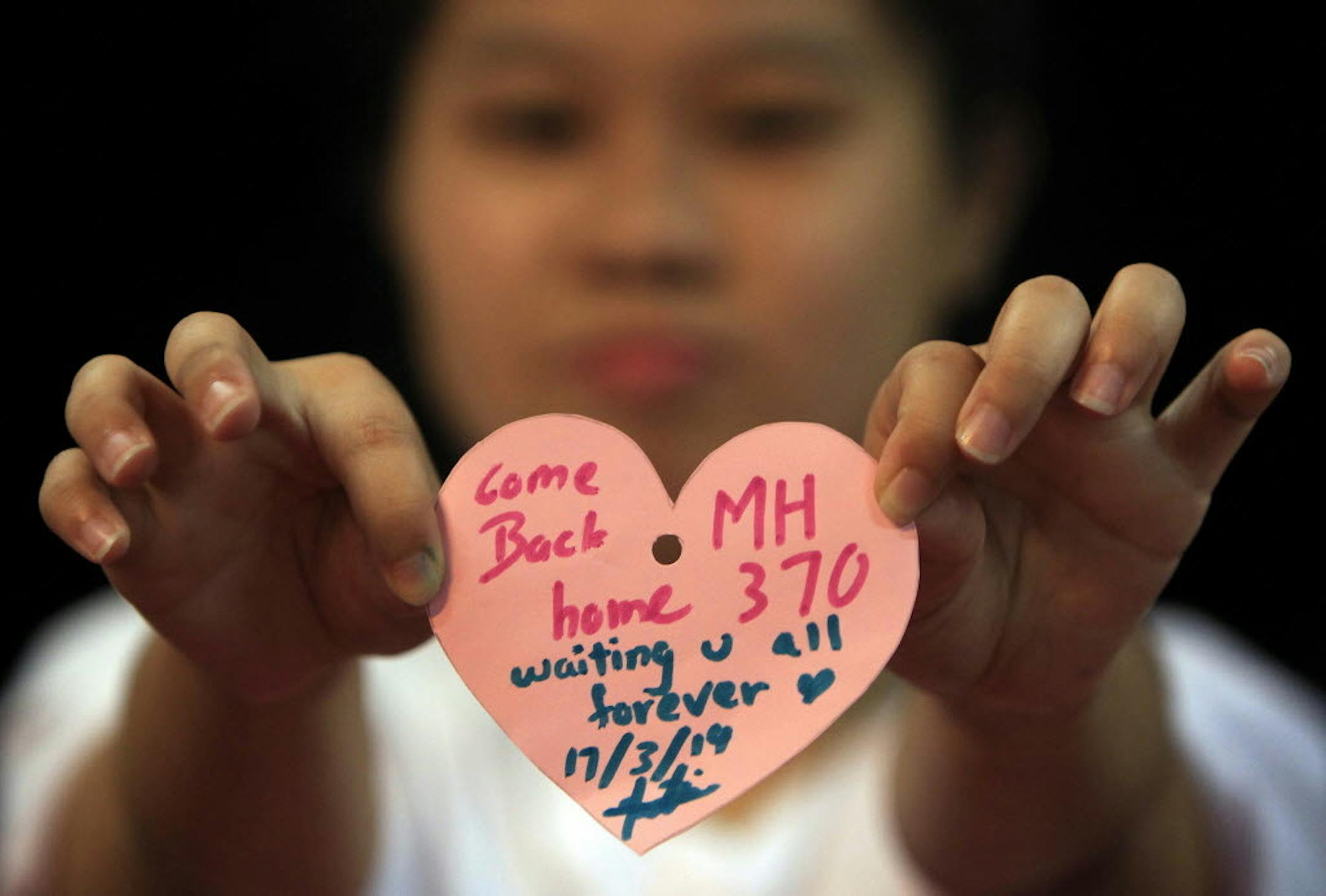 In Kuala Lumpur, Malaysia, a woman holds a heart shaped paper with messages for passengers aboard flight MH370.