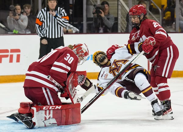 Minnesota forward Abbey Murphy (18) is brought down by Wisconsin forward Kirsten Simms (27) in front of goaltender Cami Kronish (30) in the second per