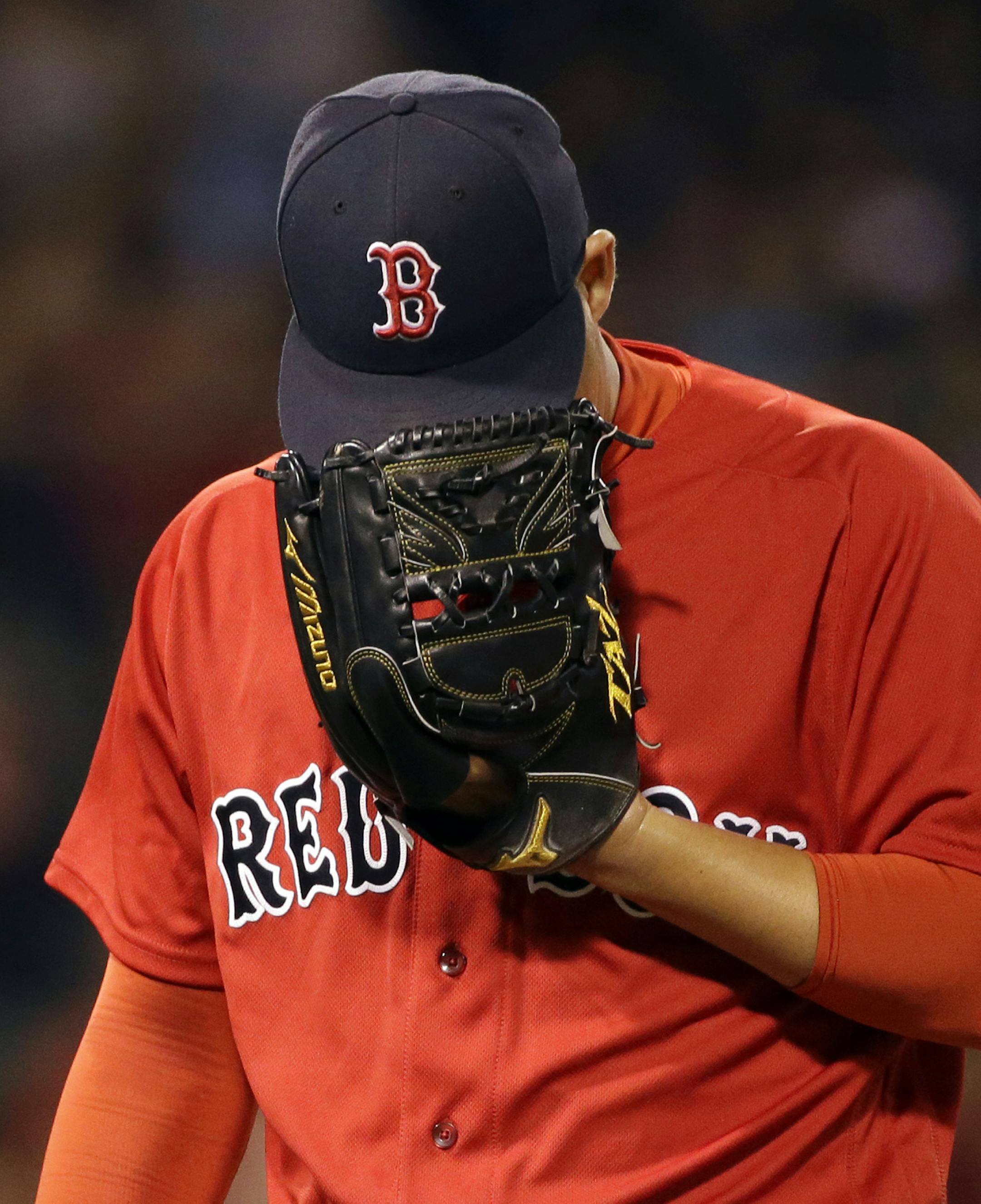 Boston Red Sox relief pitcher Junichi Tazawa hides his face in his glove as he walks to the dugout after the eighth inning of a baseball game against the Minnesota Twins at Fenway Park, Friday, July 22, 2016, in Boston. (AP Photo/Elise Amendola)