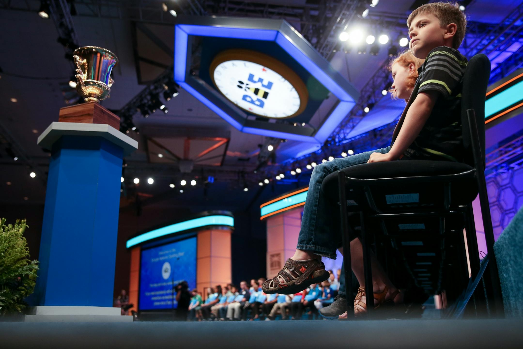 The championship trophy sits in front of spellers, including Cameron Keith, 9, of Boulder, Colo., right, as they await the start of the preliminaries of the Scripps National Spelling Bee to start, Wednesday, May 27, 2015, in Oxon Hill, Md.