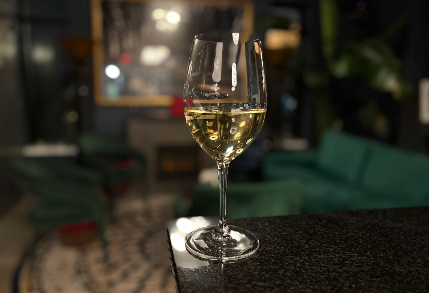 A glass of Gruner at the end of the bar with the fireplace and lounge in the background.