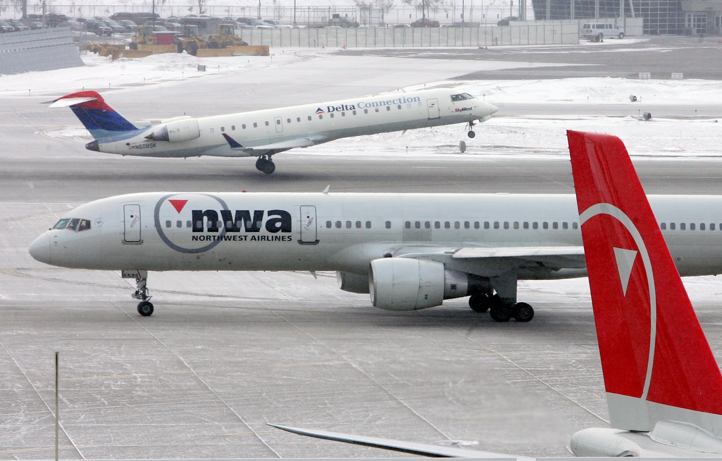 A Delta Connection flight takes off as a Northwest Airlines plane taxis Tuesday at the Minneapolis-St. Paul International Airport.