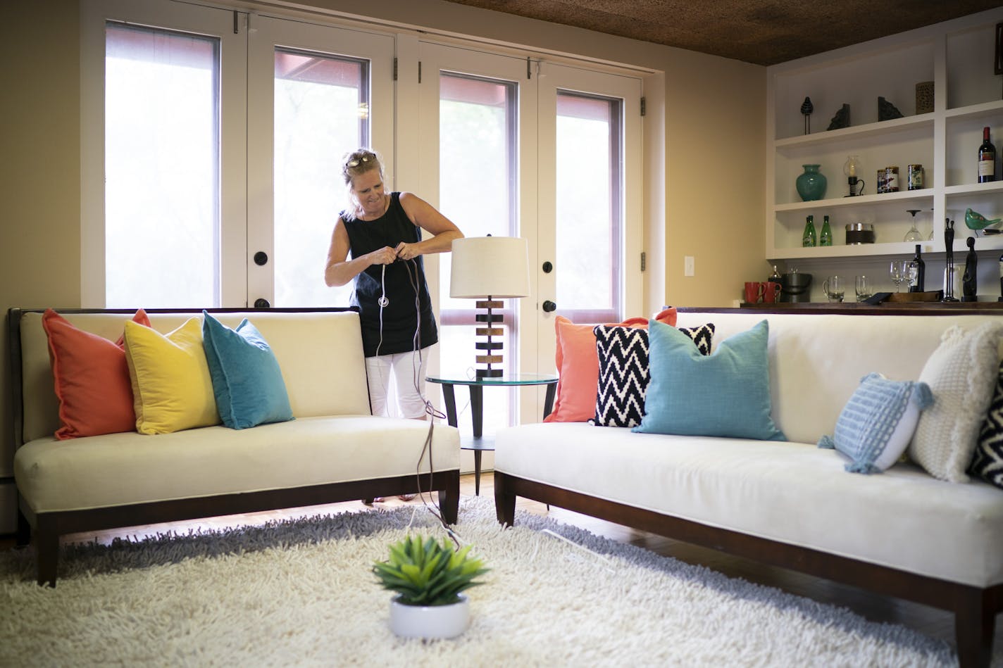 Anita Rockwell plugged in a lamp in the family room of a St. Louis Park home she staged Wednesday. ] JEFF WHEELER &#x2022; jeff.wheeler@startribune.com Anita Rockwell, whose company Stage Works readies homes for sale, has been extra busy with the fall market in full swing. She staged a home in St. Louis Park Wednesday afternoon, September 18, 2019. She brought in all the furnishings shown.