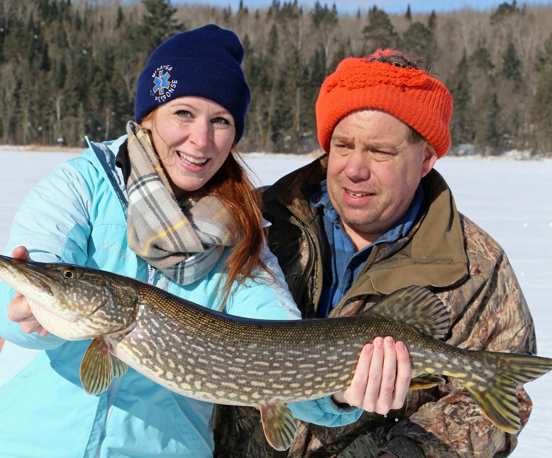 Megan Malone of Menagha, Minn., left, caught a northern pike while fishing a private lake being studied by Dallas Hudson, right, and others, in conjunction with the DNR and the U.S. Geological Survey.