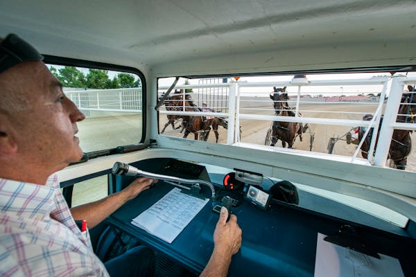 John Betts, sitting backwards facing the horses, runs the starter's car for the harness races as his wife Sandy steers