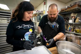 Alise McGregor, owner of YoYo Donuts, works with Kyle Baker of Thirsty Whale Bakery. McGregor bought the bakery after reading about its sudden closure