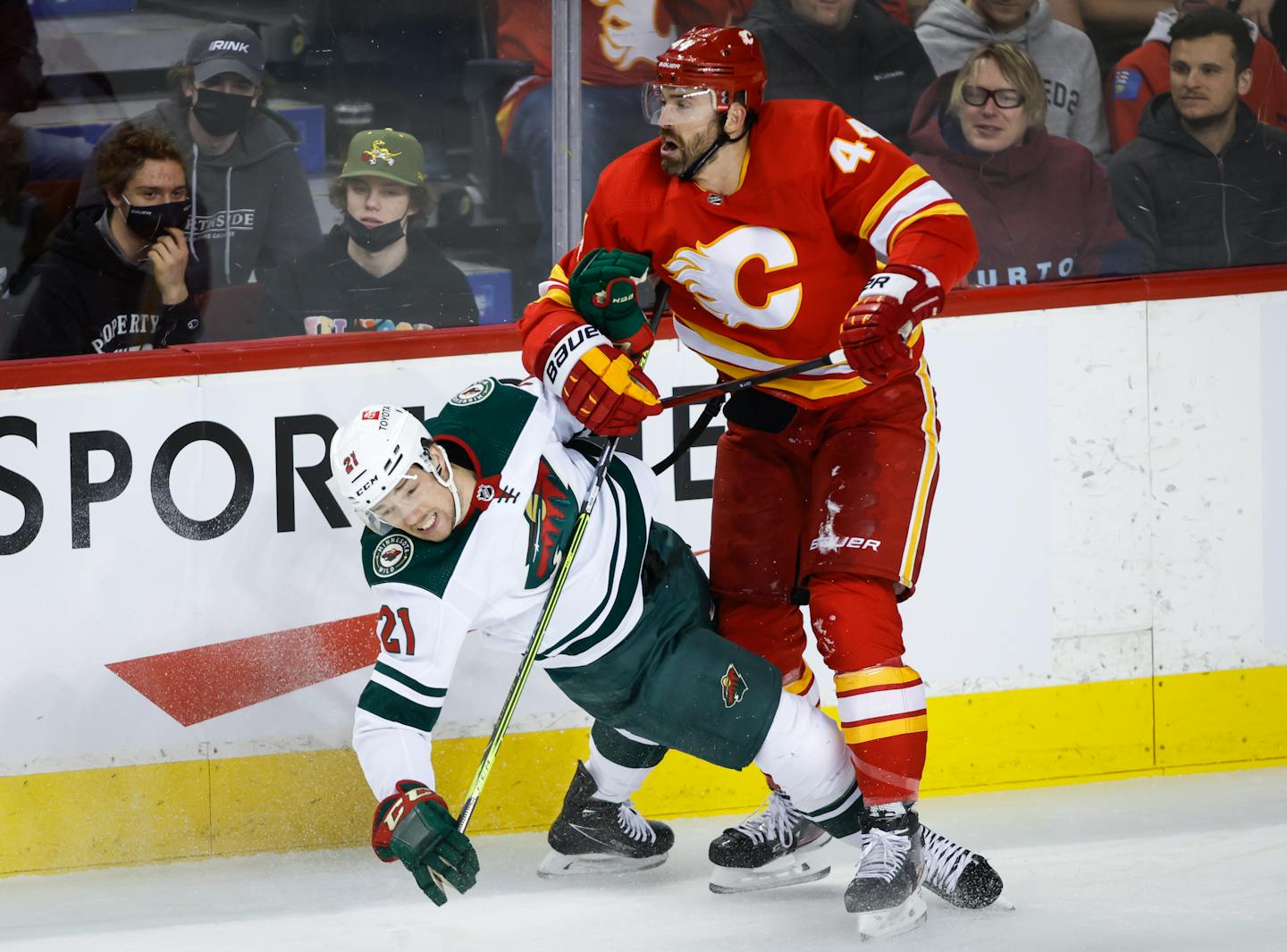 Minnesota Wild's Brandon Duhaime, left, is checked by Calgary Flames' Erik Gudbranson during the first period of an NHL hockey game Saturday, Feb. 26, 2022, in Calgary, Alberta. (Jeff McIntosh/The Canadian Press via AP)