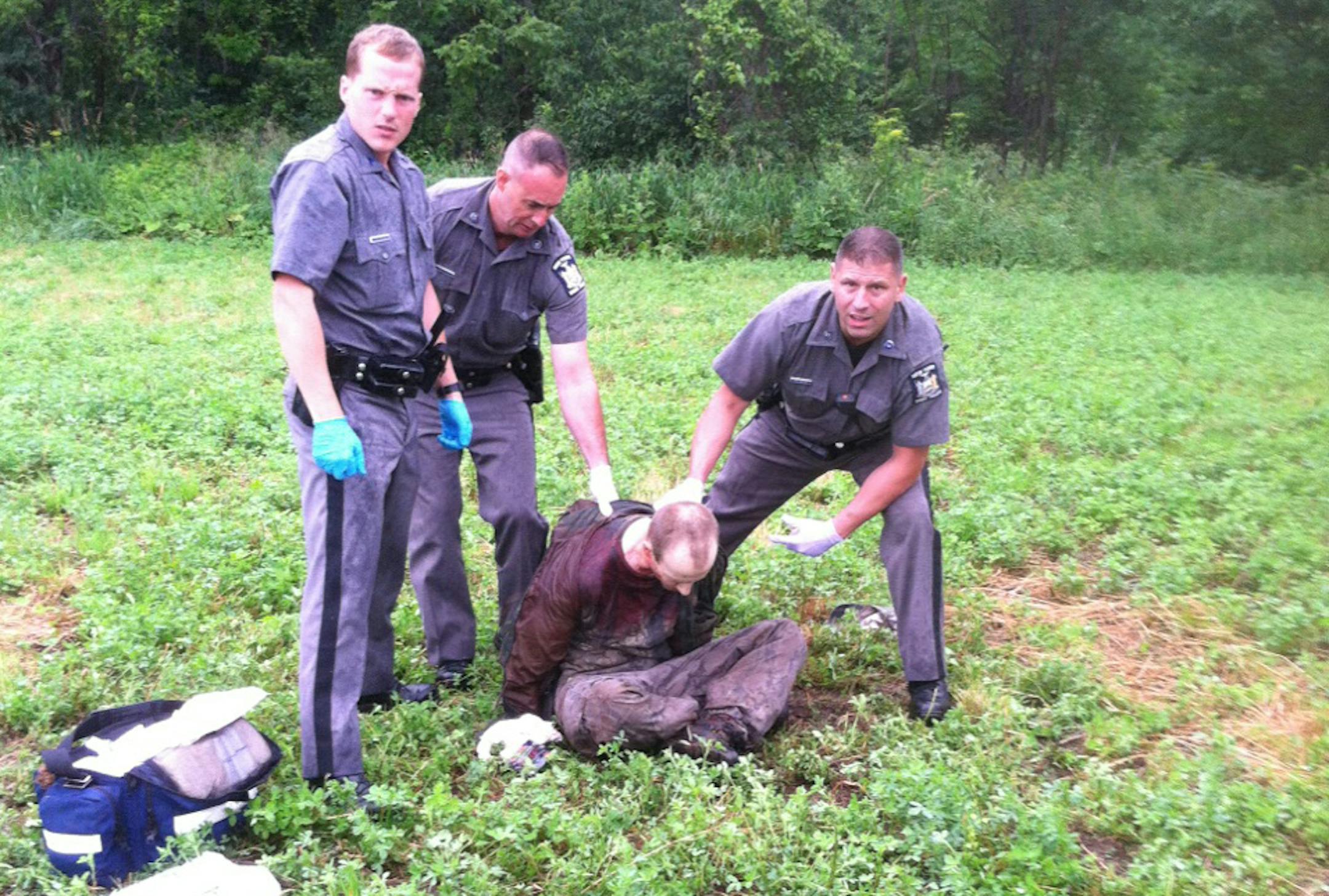 Police stand over David Sweat after he was shot and captured near the Canadian border Sunday, June 28, 2015, in Constable, N.Y.