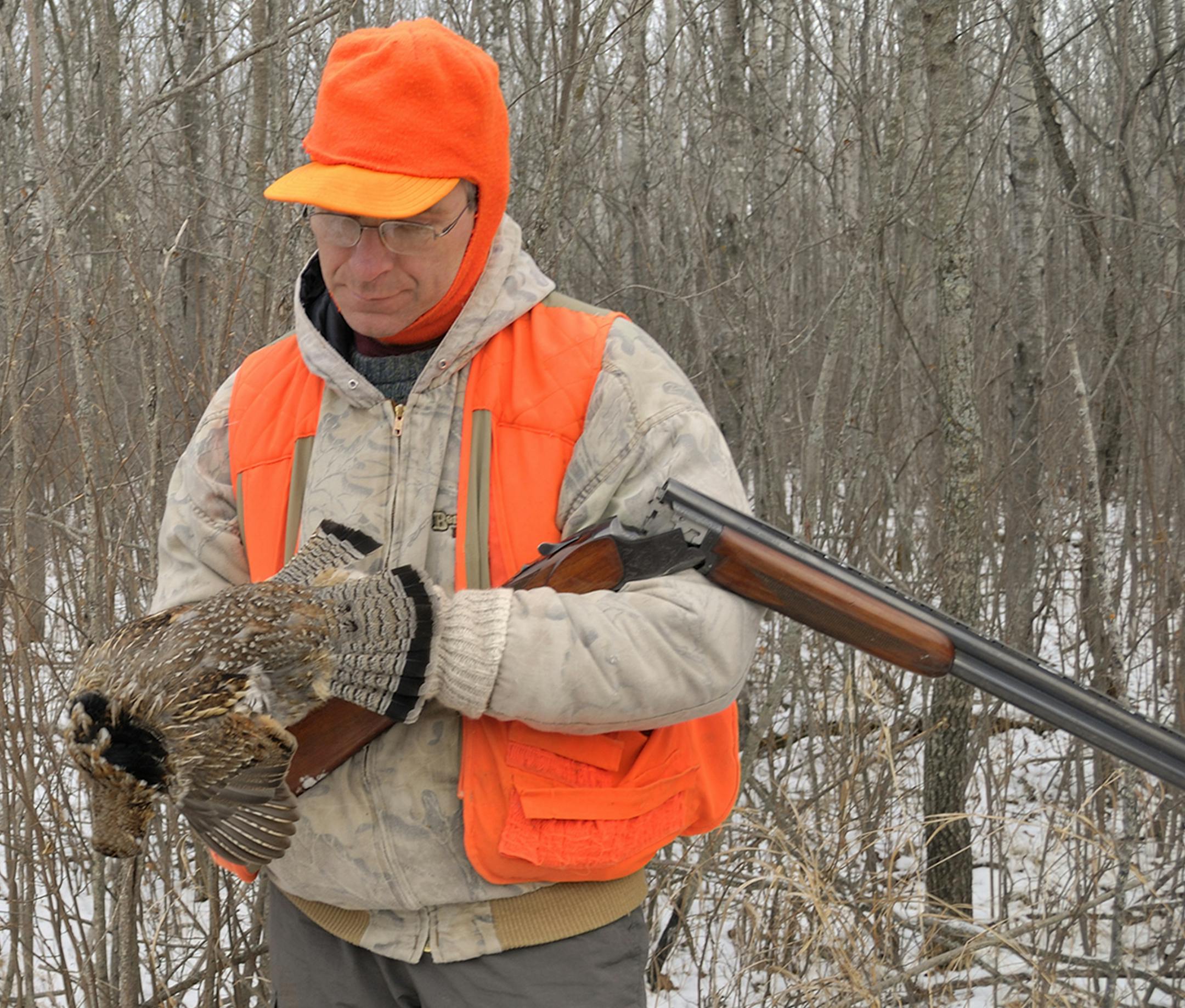 A hunter inspected a bagged grouse during a late-season hunt on snowy ground.