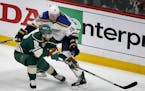 The Minnesota Wild's Jason Zucker (16) and the St. Louis Blues' Jay Bouwmeester (19) battle for the puck in the first period of Game 1 of the Western 