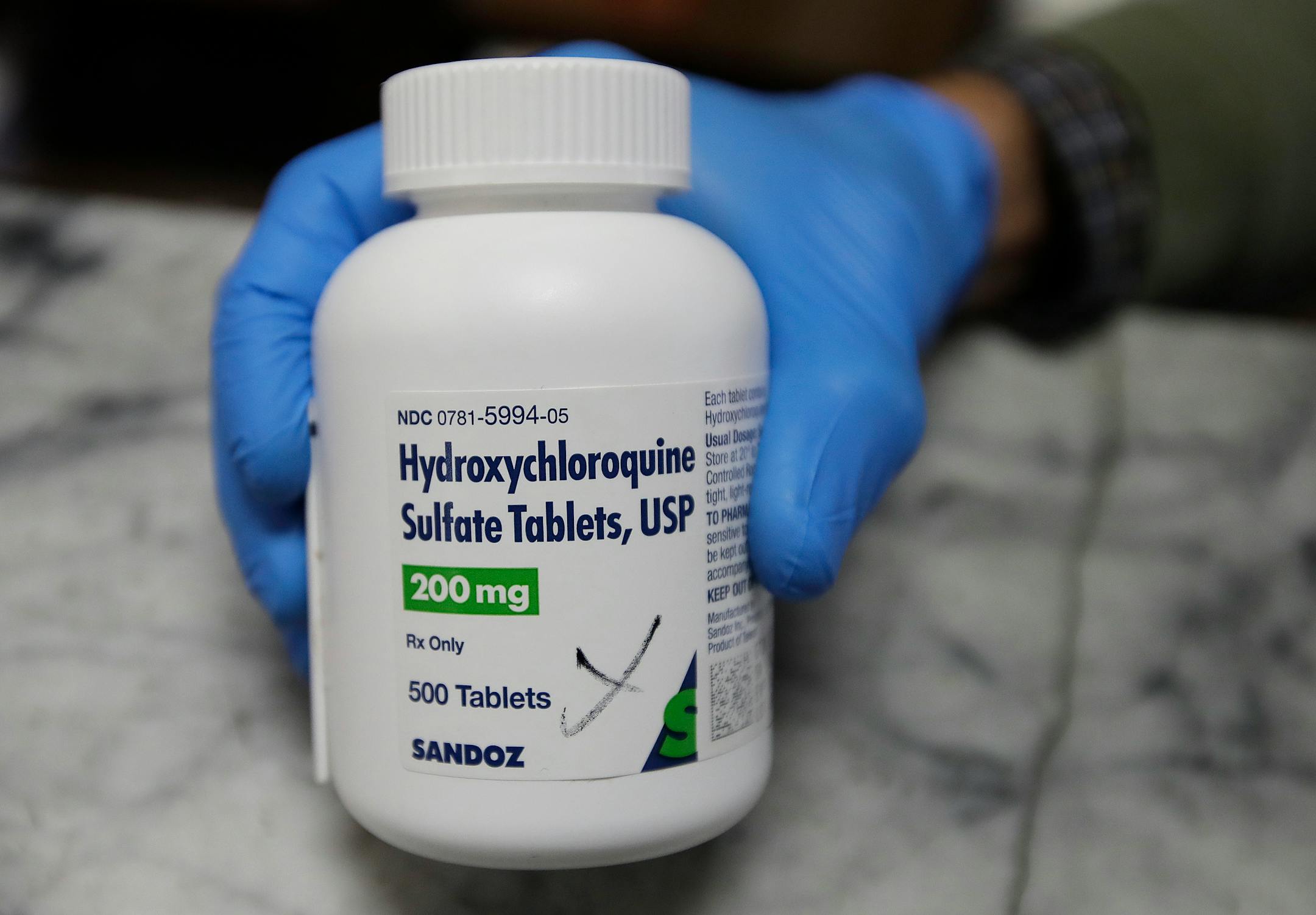 A pharmacist shows a bottle of the drug hydroxychloroquine.