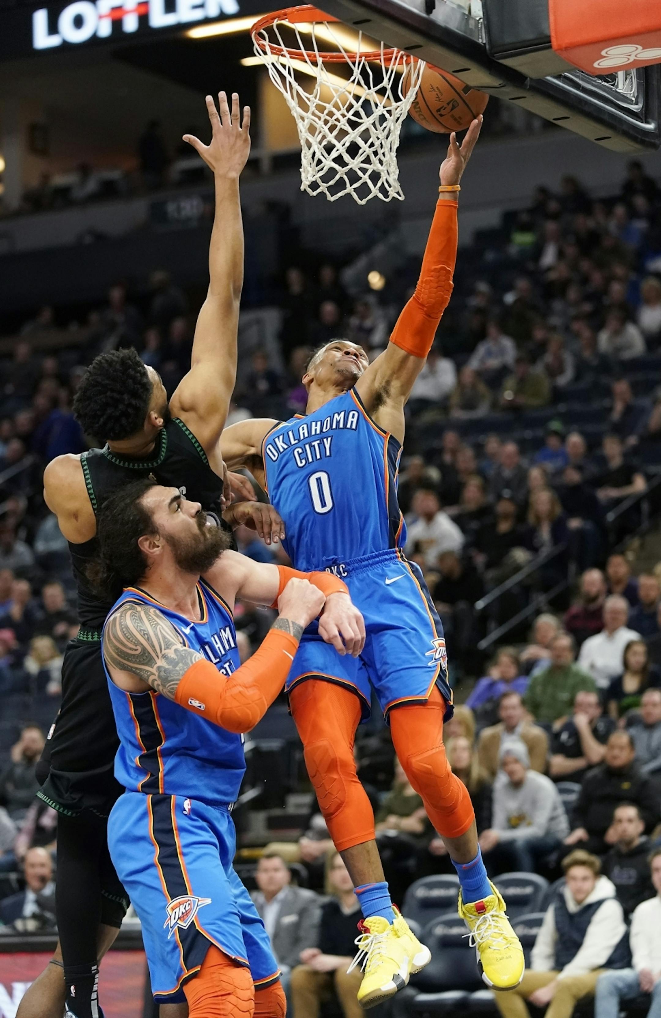 Oklahoma City Thunder guard Russell Westbrook (0) shoots as Minnesota Timberwolves center Karl-Anthony Towns (32) defends and Oklahoma City Thunder center Steven Adams (12) blocks during the second half.