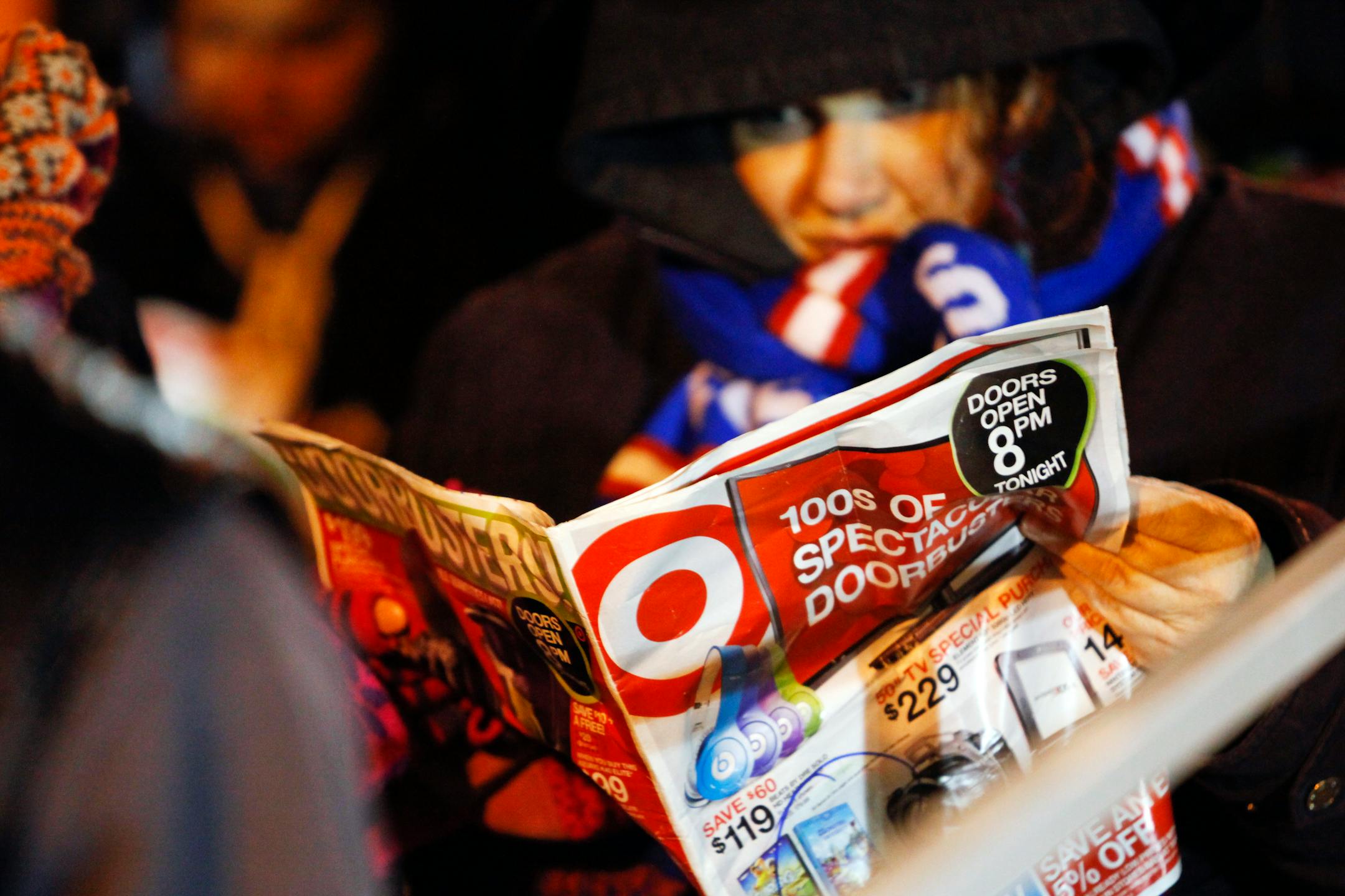 A customer reads a brochure as she waits in line outside a Target Corp. store ahead of Black Friday in Chicago, Illinois, U.S., on Thursday, Nov. 28, 2013. U.S. retailers will kick off holiday shopping earlier than ever this year as stores prepare to sell some discounted items at a loss in a battle for consumers. Photographer: Patrick T. Fallon/Bloomberg