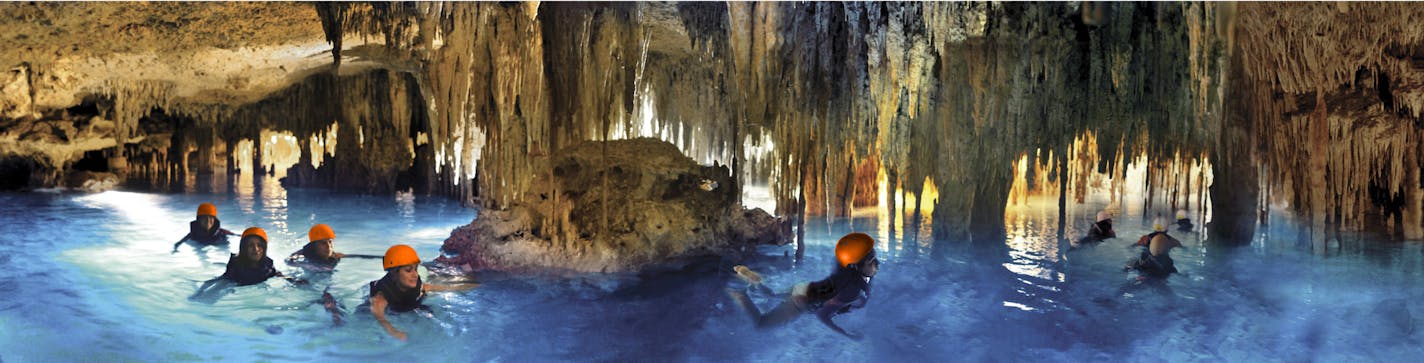 At top, rappelling makes for a dramatic entry to the subterranean world of cenotes, whose waters are clear because they have filtered through the ground. Above, visitors swim in an underground river at Xplor, an adventure park near Playa del Carmen.