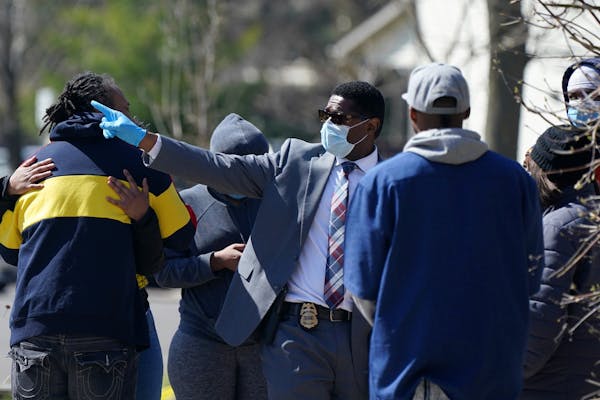 Sgt. Christopher Gaiters, center, talked with bystanders at the scene of a homicide Saturday in the 1100 block of Irving Avenue N. in Minneapolis.