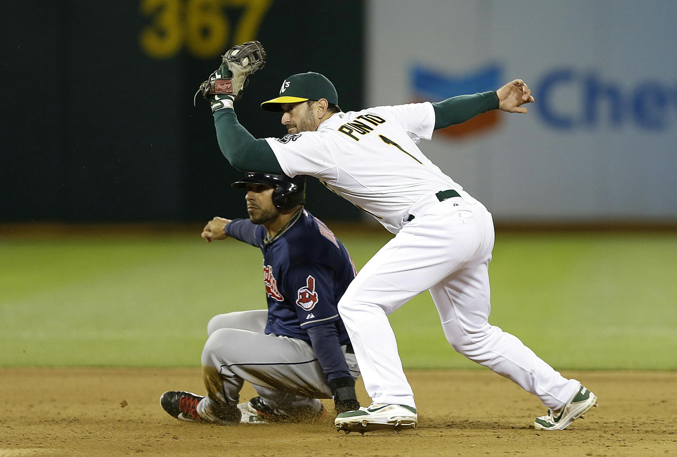 Cleveland Indians' Mike Aviles, left, slides into second base under the tag of Oakland Athletics second baseman Nick Punto (1) during the sixth inning of a baseball game in Oakland, Calif., Wednesday, April 2, 2014. Aviles was initially called out at second base but was ruled safe after manager Terry Francona challenged the ruling and umpires reversed the call. (AP Photo/Jeff Chiu)