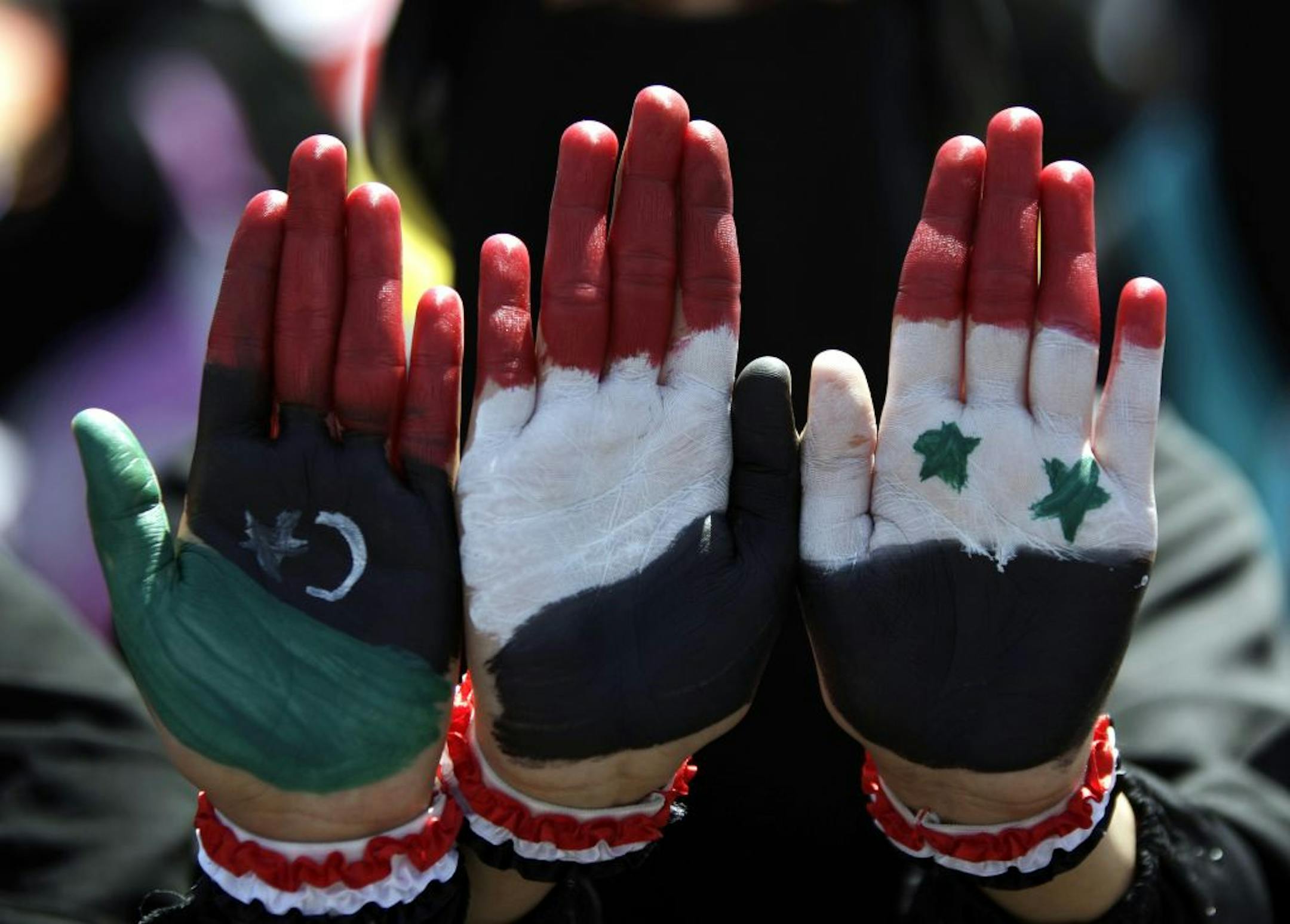 Yemeni female protestors show their hands with colors of th pre-Gadhafi Libya, Yemen and Syria flags during a demonstration demanding the resignation of Yemeni President Ali Abdullah Saleh in Sanaa, Yemen, Friday, Oct. 21, 2011.