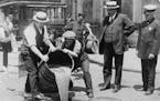 An undated handout photo of New York City police official watching agents pour liquor into a sewer following a raid during the Prohibition era, around