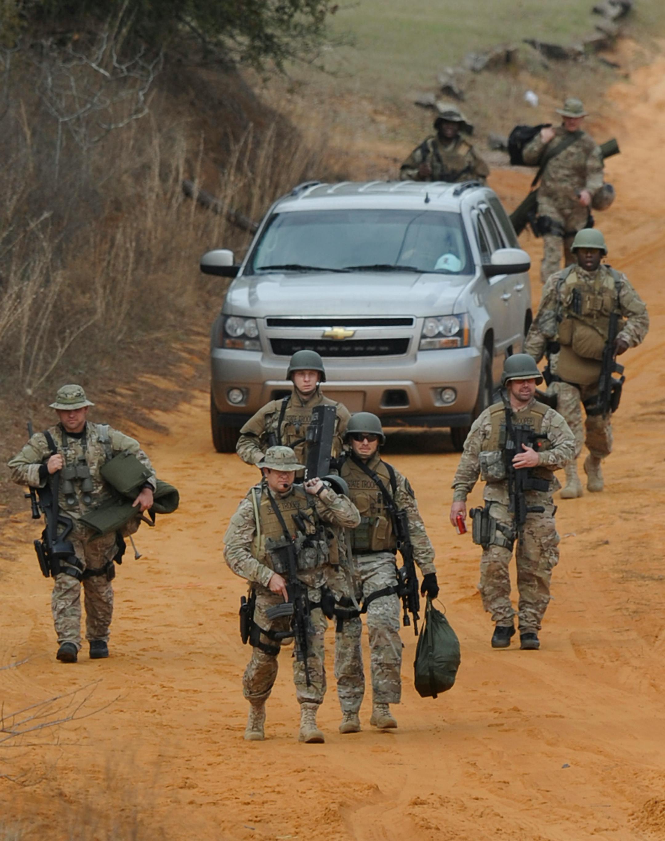 Heavily armed men come back down the hill from the direction of the suspect's home at the Dale County hostage scene near Ozark, Ala. on Wednesday Jan. 30, 2013.