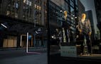 In this Monday, March 23, 2020, photo, mannequins in the window of Hubert White are seen at night with deserted streets during the coronavirus outbrea