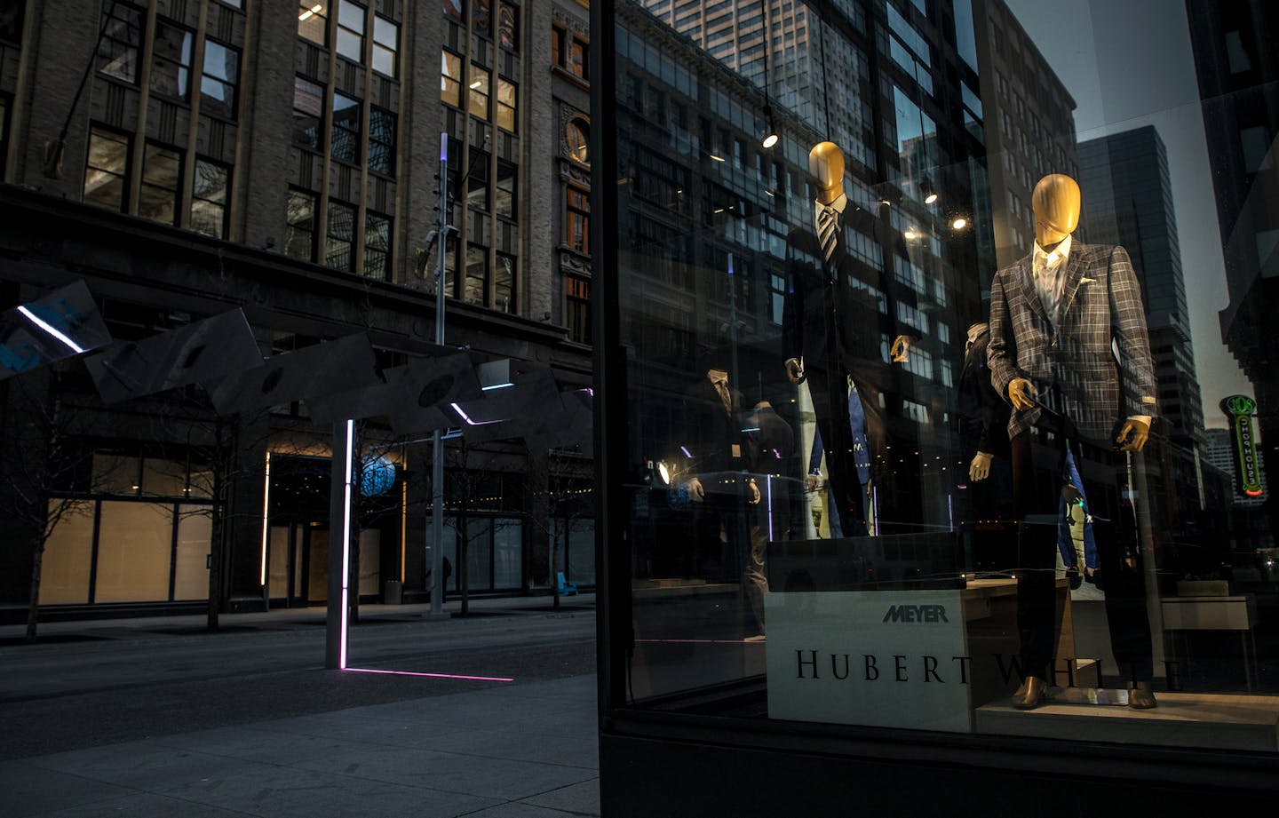 In this Monday, March 23, 2020, photo, mannequins in the window of Hubert White are seen at night with deserted streets during the coronavirus outbreak at Nicollet Mall in downtown Minneapolis. (Carlos Gonzalez/Star Tribune via AP)