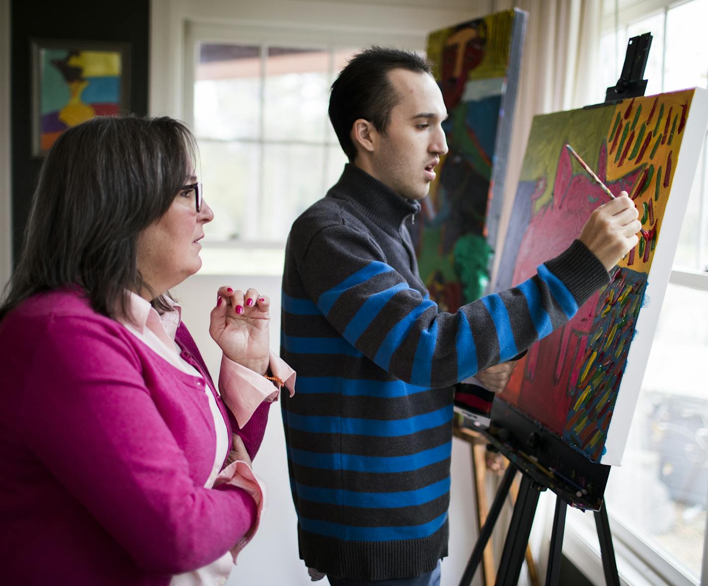 Jimmy Reagan paints as his mother Peg Reagan watches inside their home. ] LEILA NAVIDI &#xef; leila.navidi@startribune.com BACKGROUND INFORMATION: Artist Jimmy Reagan at home in Mendota Heights on Thursday, October 26, 2017. Jimmy Reagan, a 24-year-old autistic artist shares his unique view on life in his paintings and sculptures, which are shown and sold internationally.