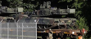 Military police walk near Abrams tanks on a flat car in a rail yard, Monday, July 1, 2019, in Washington, ahead of a Fourth of July celebration that P