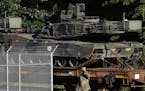 Military police walk near Abrams tanks on a flat car in a rail yard, Monday, July 1, 2019, in Washington, ahead of a Fourth of July celebration that P