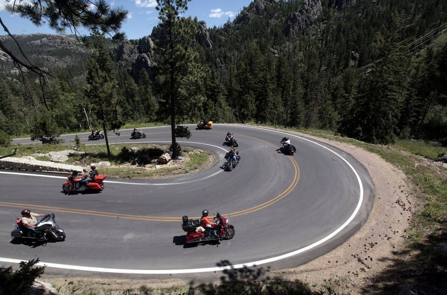 In this photo taken July 30, 2015, motorcycle riders make their way around one of the hairpin turns on state Highway 87 outside Sylvan Lake near Hill City, S.D.