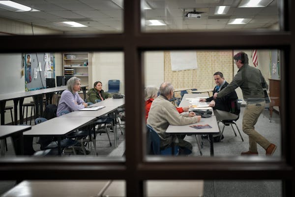 Caucus convener Will Waggoner, right, hands out forms at the start of a precinct meeting, as David Johnson, left, listens Tuesday, Feb. 27, 2024  Hast