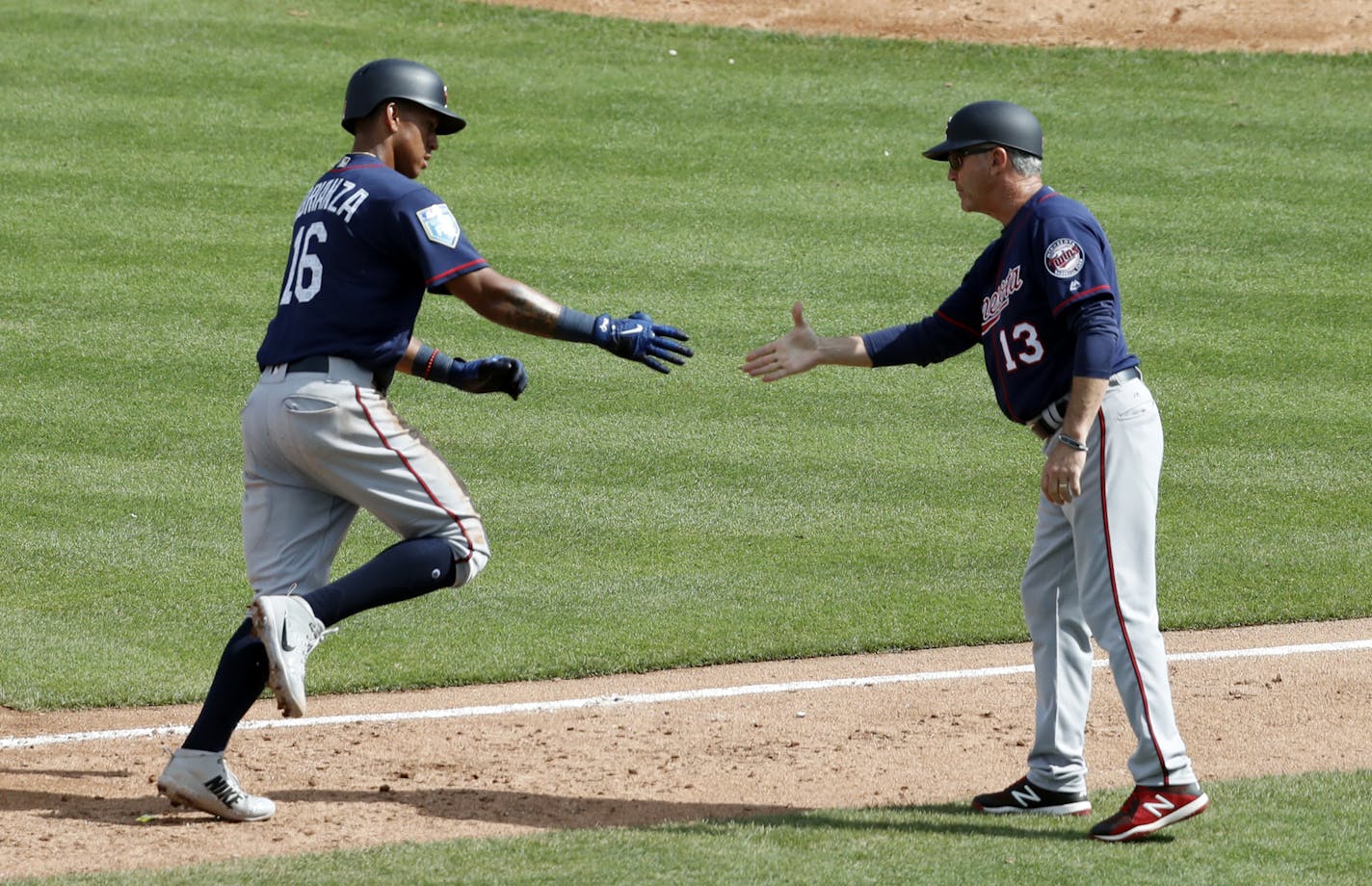 Minnesota Twins' Ehire Adrianza (16) is congratulated by third base coach Gene Glynn (13) after hitting a two-run home run during the fifth inning of an exhibition spring training baseball game against the St. Louis Cardinals, Thursday, March 1, 2018, in Jupiter, Fla. (AP Photo/Jeff Roberson)