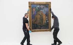 Employees place the work "Contes barbares" (Barbarian Tales) by French painter Paul Gaugin, during installation works for the upcoming exhibition in t