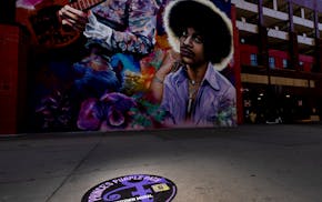 A Purple Path sidewalk sign near the Prince mural at Parking Ramp A is one of 20 such sites being installed by Meet Minneapolis.