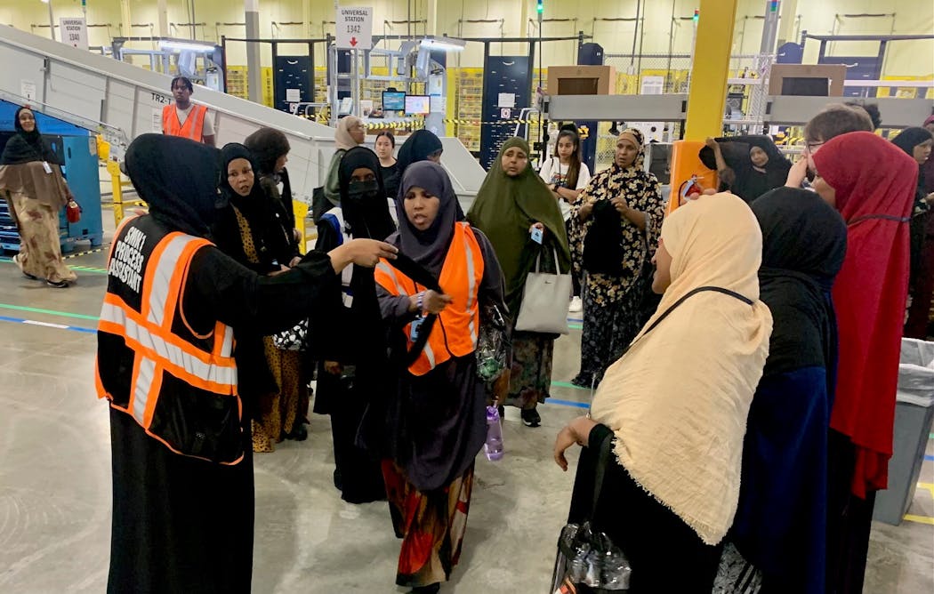 Amazon employee, Asha Ahmed, far left, handed out new company-branded hijabs to Shukri Hiret and other workers at the SN1 Brooklyn Park facility Wednesday.