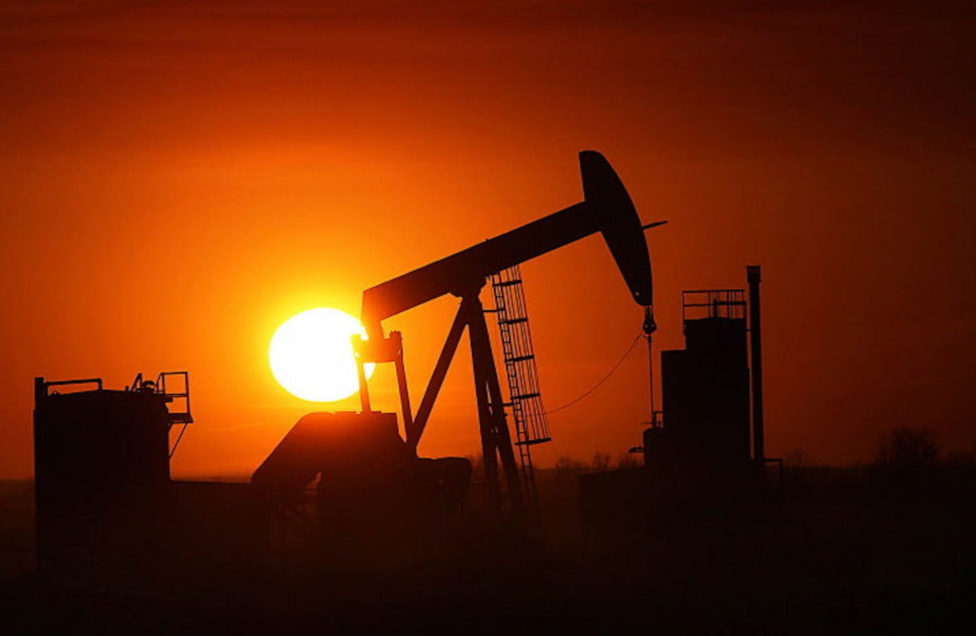 The sun set behind an oil well near Williston, N.D. The state got its 10,000th well in June, but has cut back sharply on the number of new wells drilled in response to lower prices.