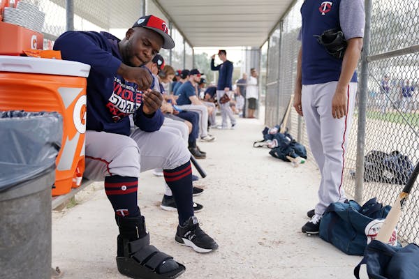 Minnesota Twins third baseman Miguel Sano (22) hung out in the dugout at the practice field as he sat out another day of workouts wearing a boot on hi