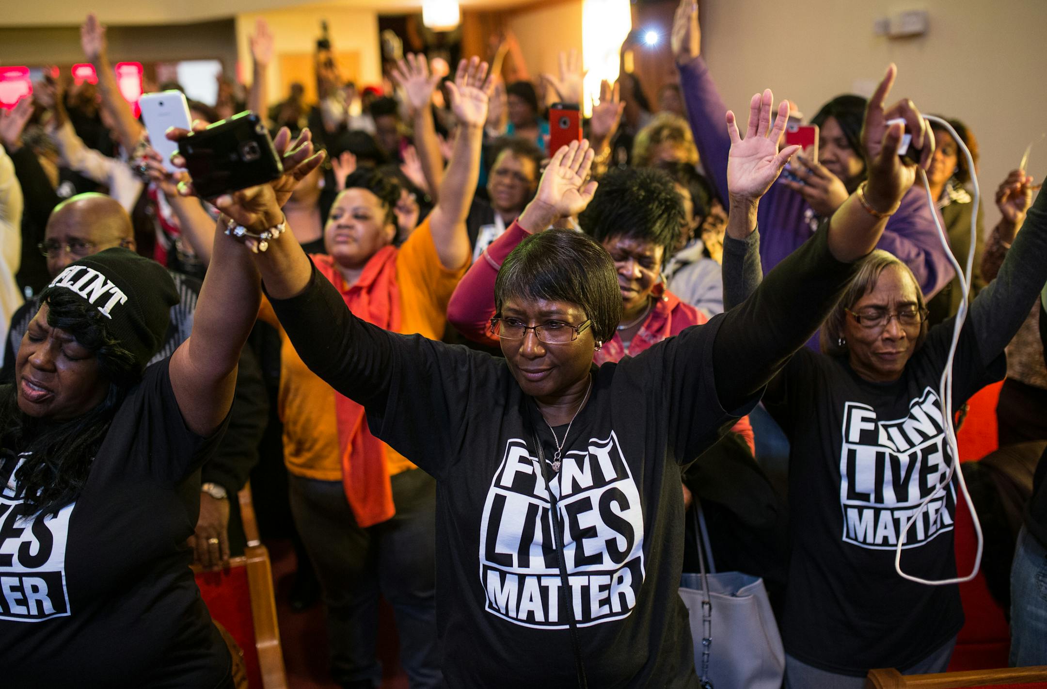 Flint residents raise their arms during a town hall meeting about the Flint water crisis on Monday, Feb. 1, 2016, at Flint Trinity Missionary Baptist Church in Flint, Mich. The Michigan Department of Environmental Quality has undertaken a five-part strategy to determine whether Flint's water, which has become contaminated with lead, is safe to drink. (Ryan Garza/Detroit Free Press via AP) DETROIT NEWS OUT; TV OUT; MAGS OUT; NO SALES; MANDATORY CREDIT DETROIT FREE PRESS