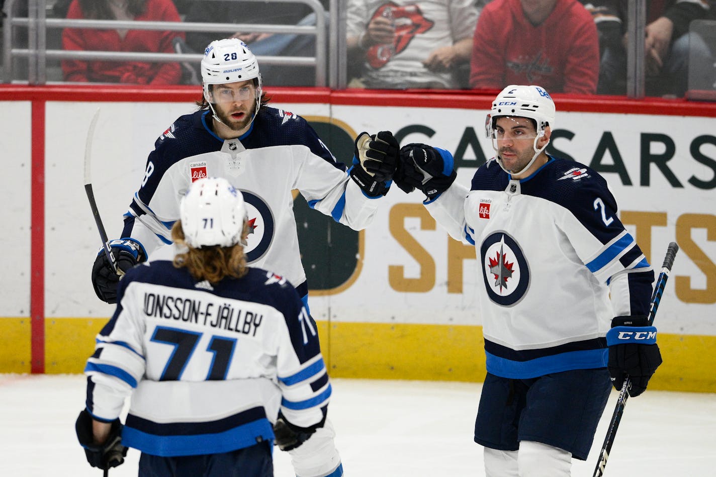 Winnipeg Jets center Kevin Stenlund (28) celebrates after his goal with left wing Axel Jonsson-Fjallby (71) and defenseman Dylan DeMelo (2) during the third period of an NHL hockey game against the Washington Capitals, Friday, Dec. 23, 2022, in Washington. (AP Photo/Nick Wass)